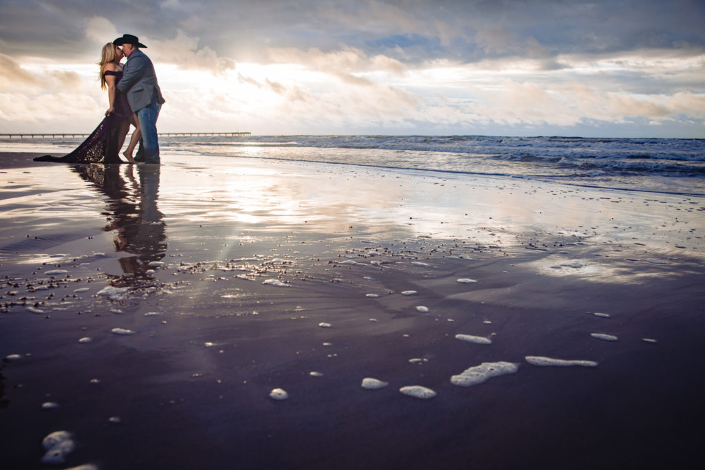 Couple embraces in formal outfits for sunrise engagement photos on the beach in Port Aransas, TX. Photography by Shannon Cain Photography