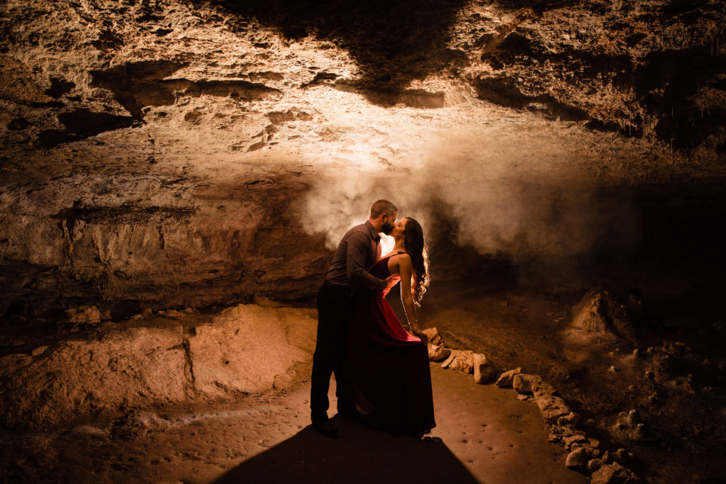 Couple poses for engagement photos in a cave at Westcave Discovery Center in formal outfits. Photography by Shannon Cain Photography