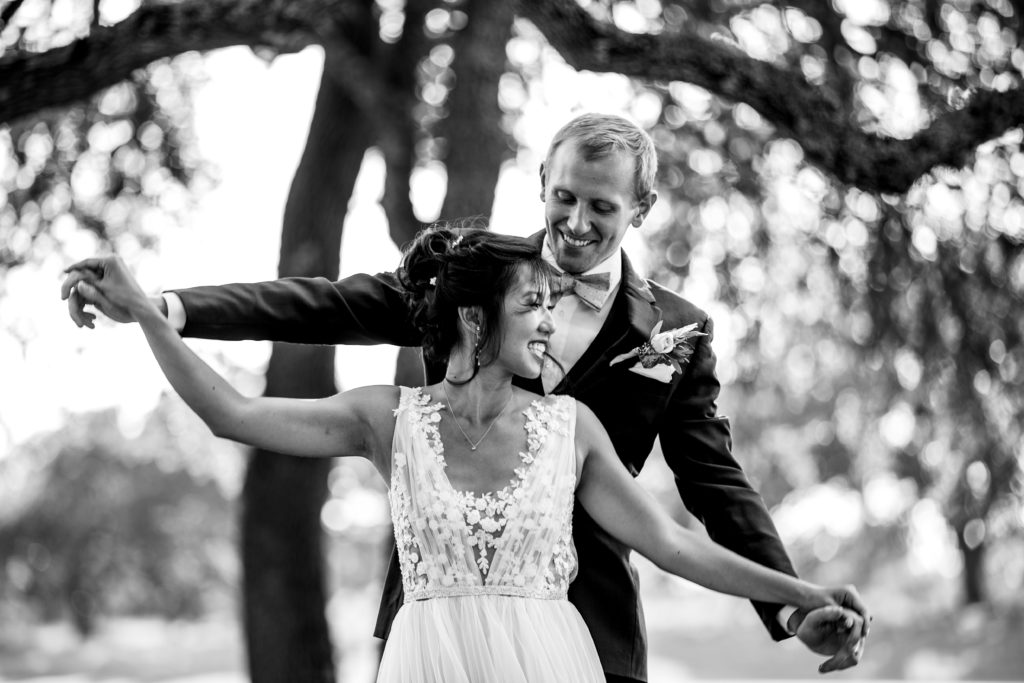 Bride and groom hold hands and dance together under oak trees at Bergheim Ranch in Boerne.  Photo by Shannon Cain Photography