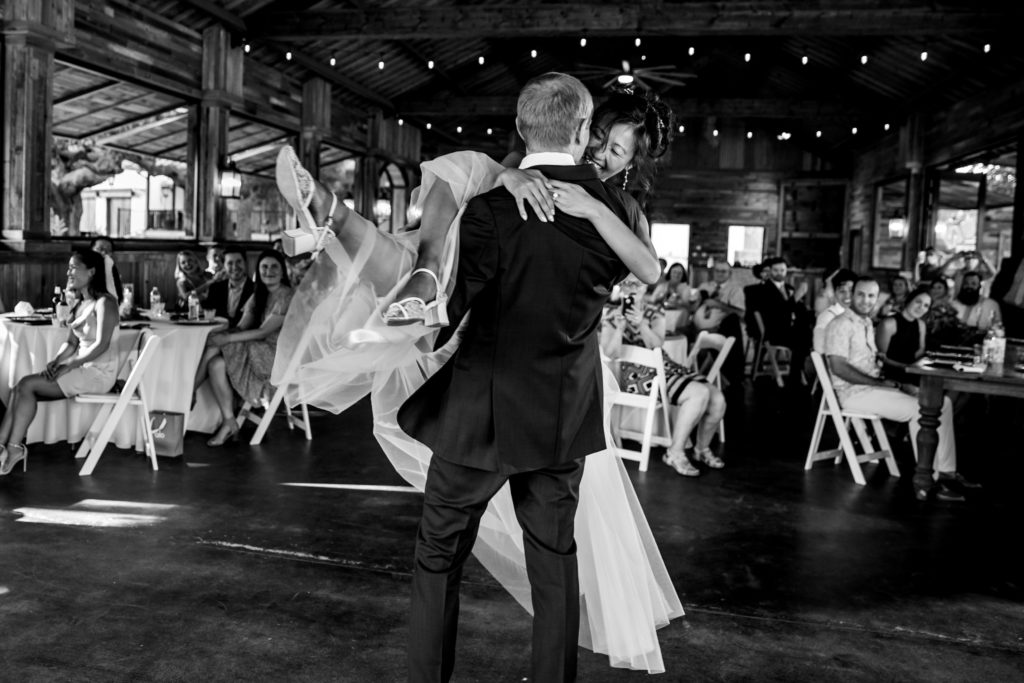 Groom lifts bride and twirls her around during first dance at Bergheim Ranch in Boerne.  Photo by Shannon Cain Photography