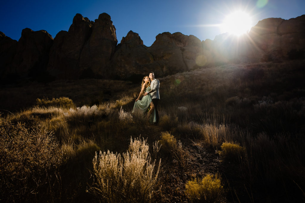 Bride and Groom embracing at The Organ Mountains in Las Cruces, NM at sunset for Adventure Engagement Session.  Photography by Shannon Cain Photography.  Hair and Makeup by Glam on Demand.