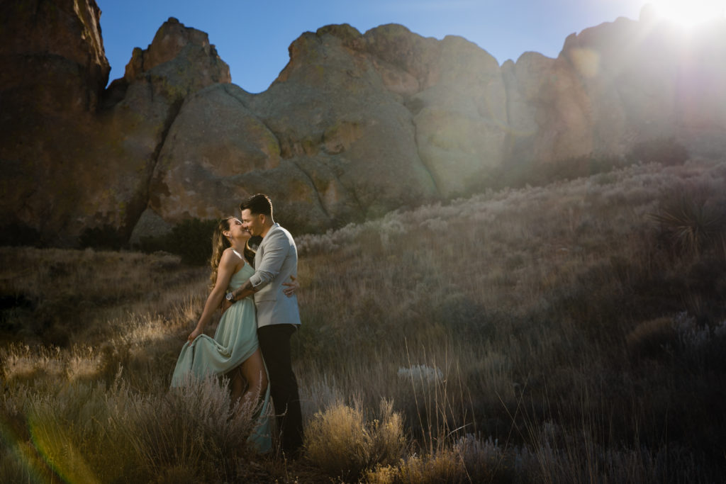 Bride and Groom embracing at The Organ Mountains- Dripping Springs- Las Cruces for Adventure Engagement Session.  Photography by Shannon Cain Photography.  Hair and Makeup by Glam on Demand.